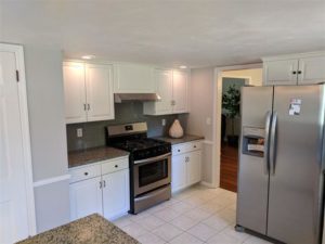 Updated kitchen with white cabinets, a dark backsplash, and stainless steel stove and refrigerator