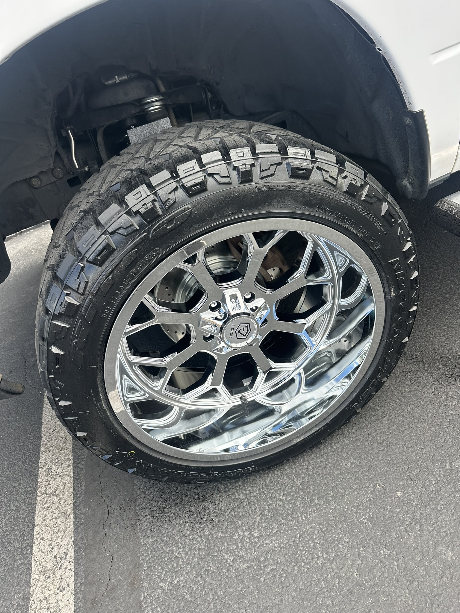 Close-up of chrome Edge wheel with 33×12.50R22 Nitto tire and brake rotor