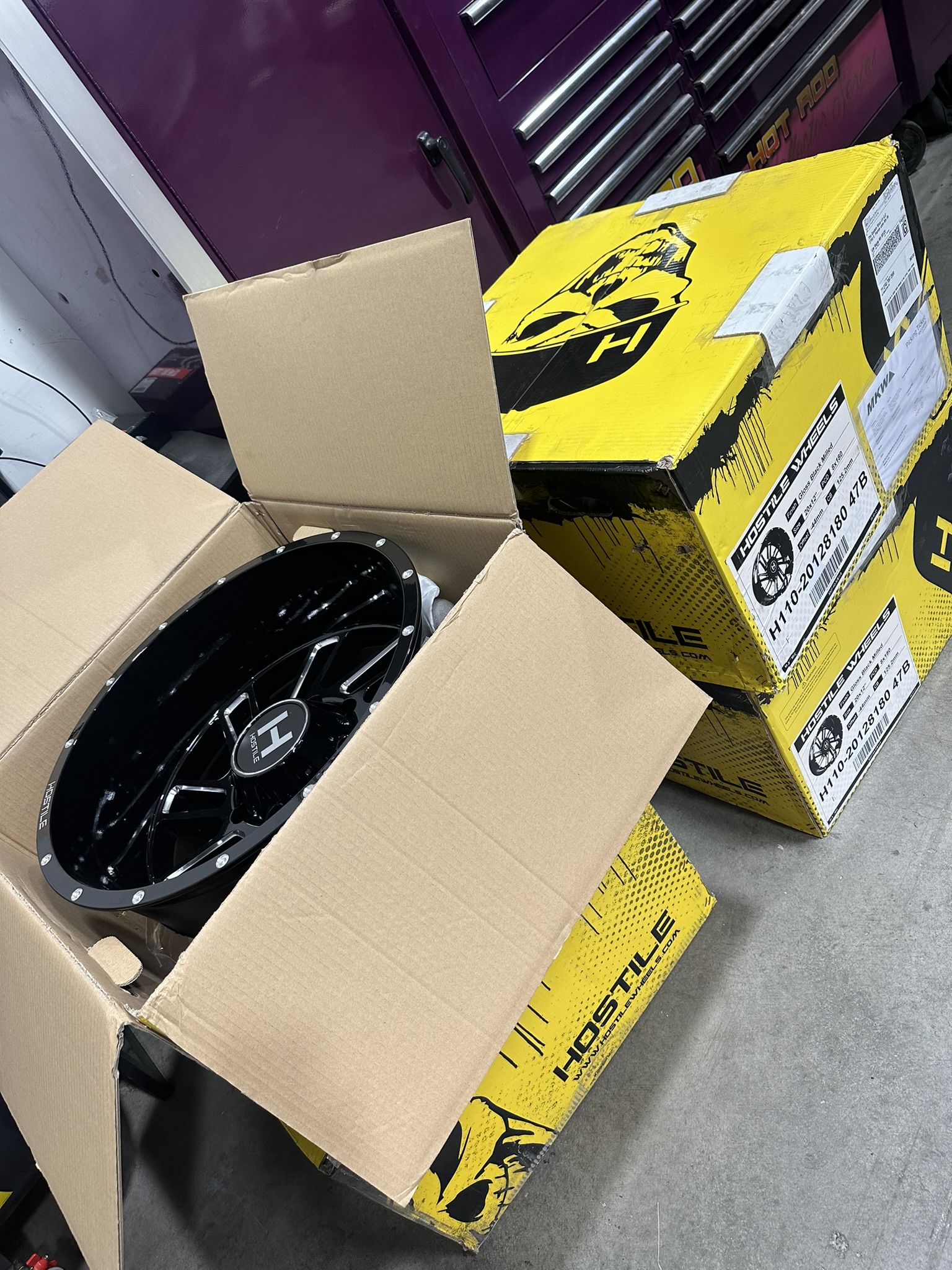 Black milled Hostile wheel unpacked beside Hostile wheel boxes
