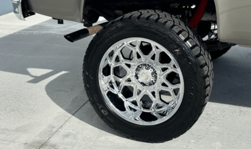 Close-up of custom chrome wheel and all-terrain tire fitment on a truck