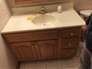 Original wood bathroom vanity and sink surrounded by pink tile