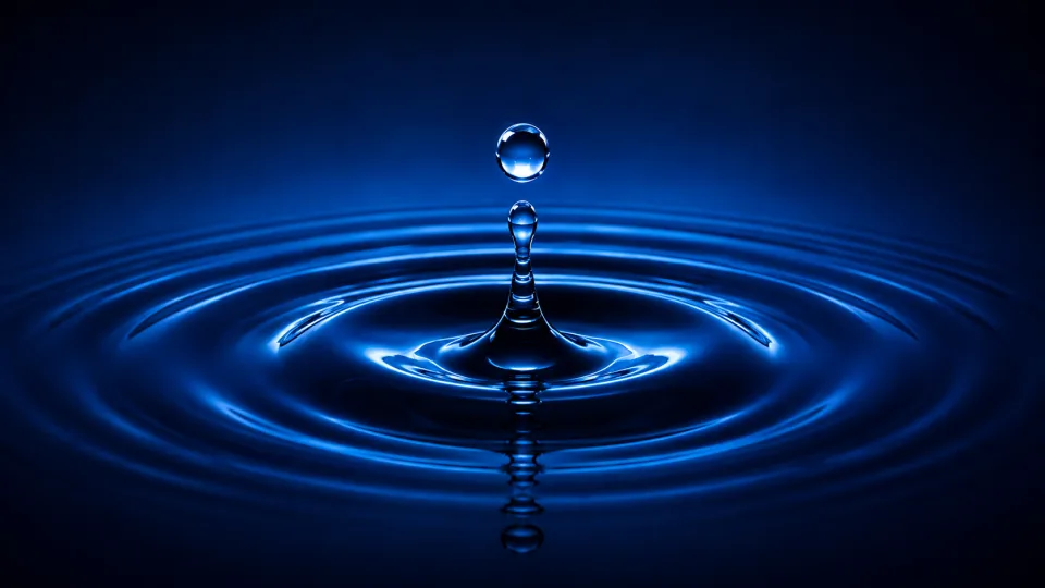 Glowing blue water droplet above rippling purified water.