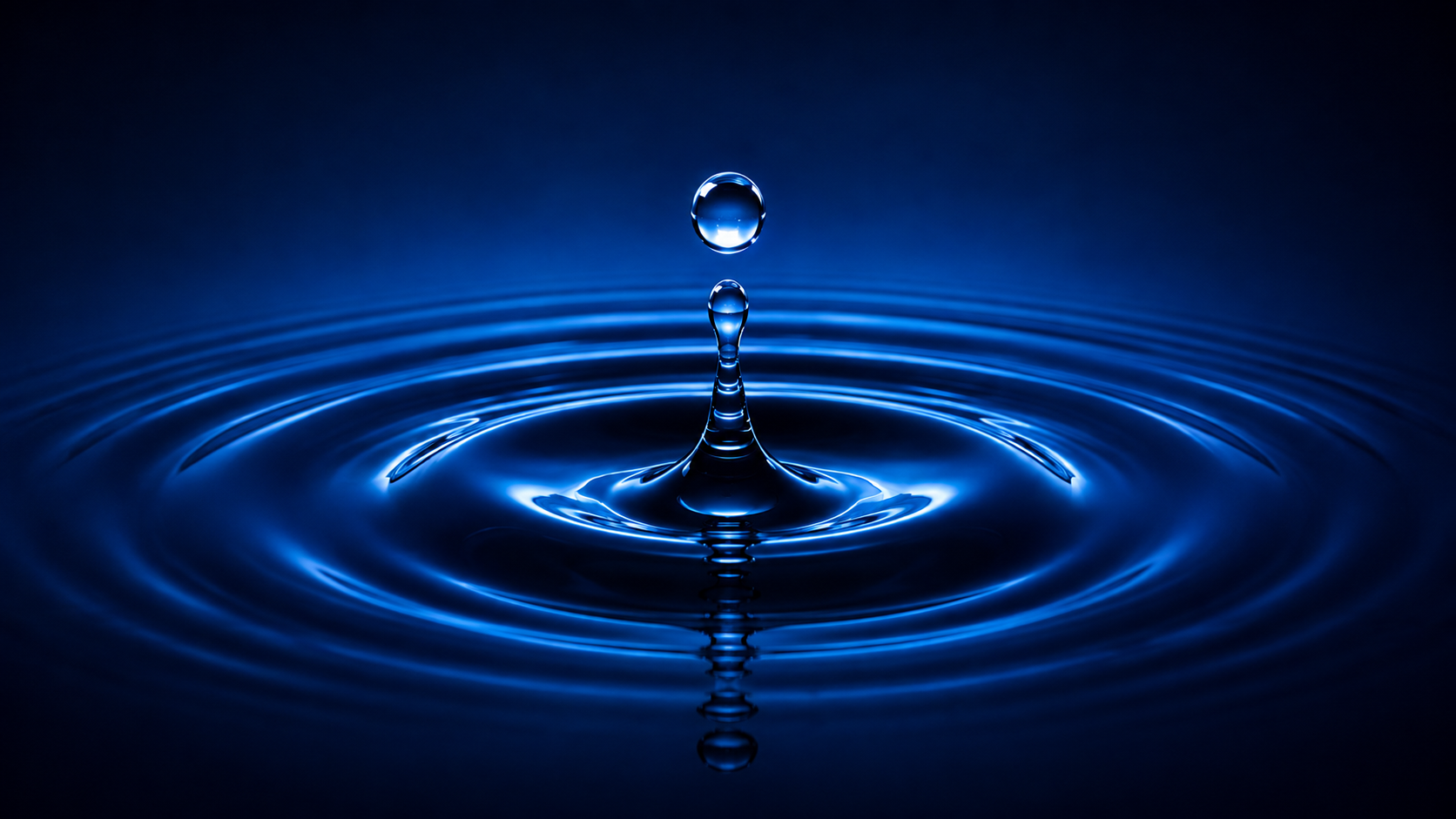 Glowing blue water droplet above rippling purified water.