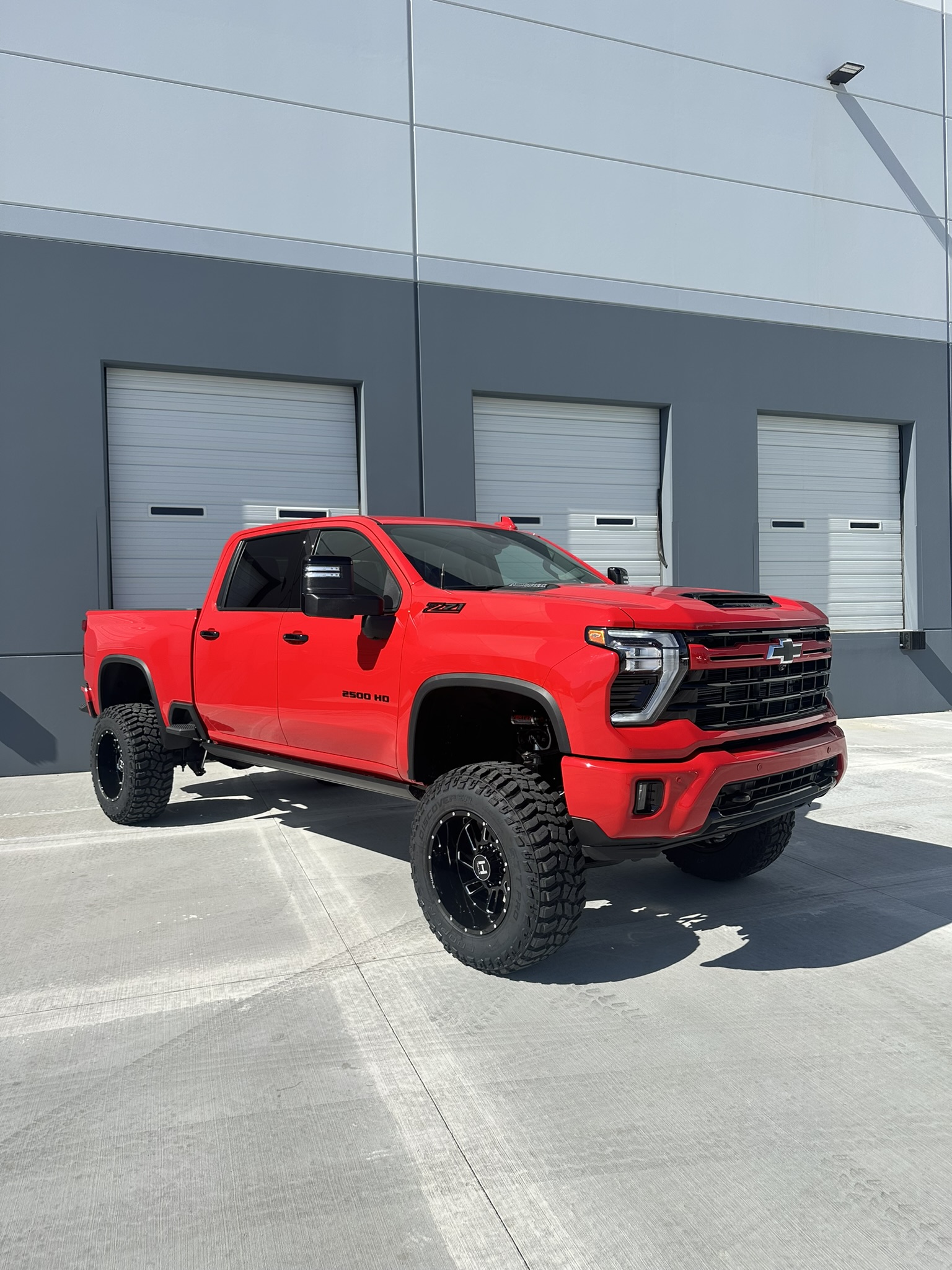Finished red 2024 Silverado 2500HD Duramax with a 7-inch lift, 37-inch tires and black Hostile wheels