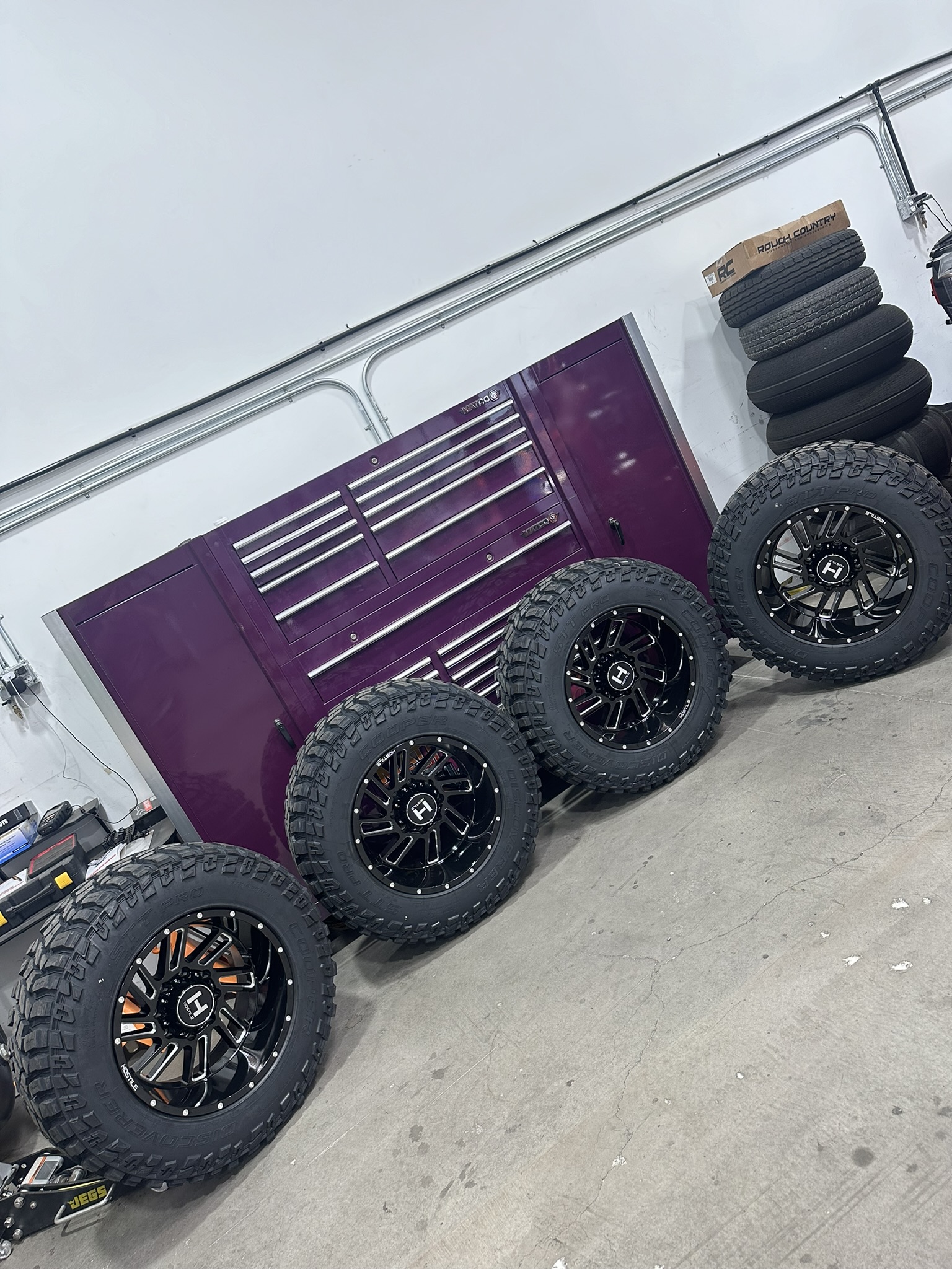 Four Hostile wheels mounted with off-road tires inside the shop