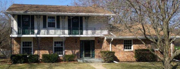 Front exterior of the two-story brick and siding home before renovation
